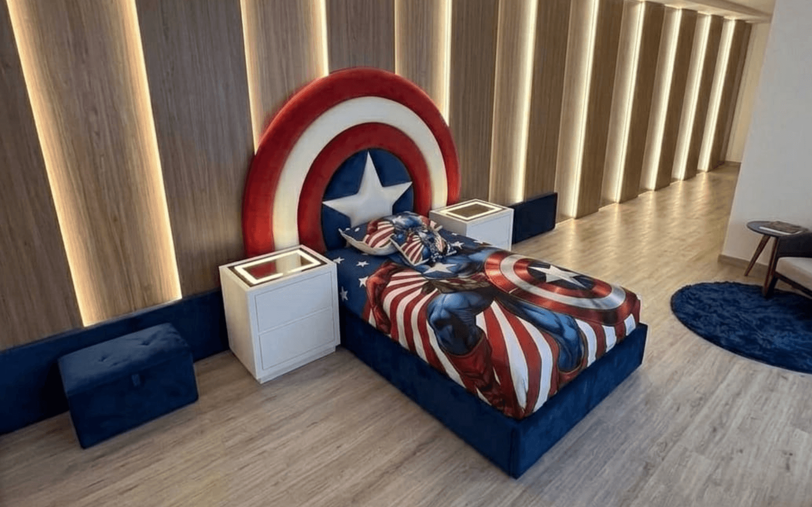 Superhero bedroom with a round red, white and blue shield headboard above a navy upholstered bed