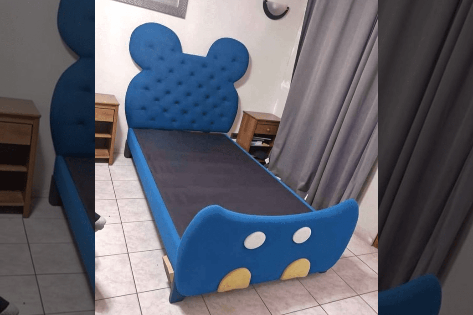 Blue tufted bed with a rounded character headboard and a white-and-yellow footboard, in a tiled bedroom between two wooden nightstands